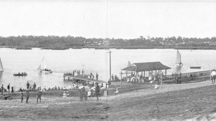 Black and white landscape photo of a lake with people and boats 